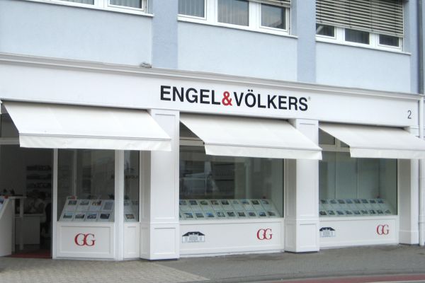 Die Außenfassade des Immobilienbüros besticht durch elegante Glasfenster mit Immobilienanzeigen, ergänzt durch fachmännisch installierte Markise-Markisen, die die Fachbetrieb-Handwerkskunst des Unternehmens widerspiegeln.